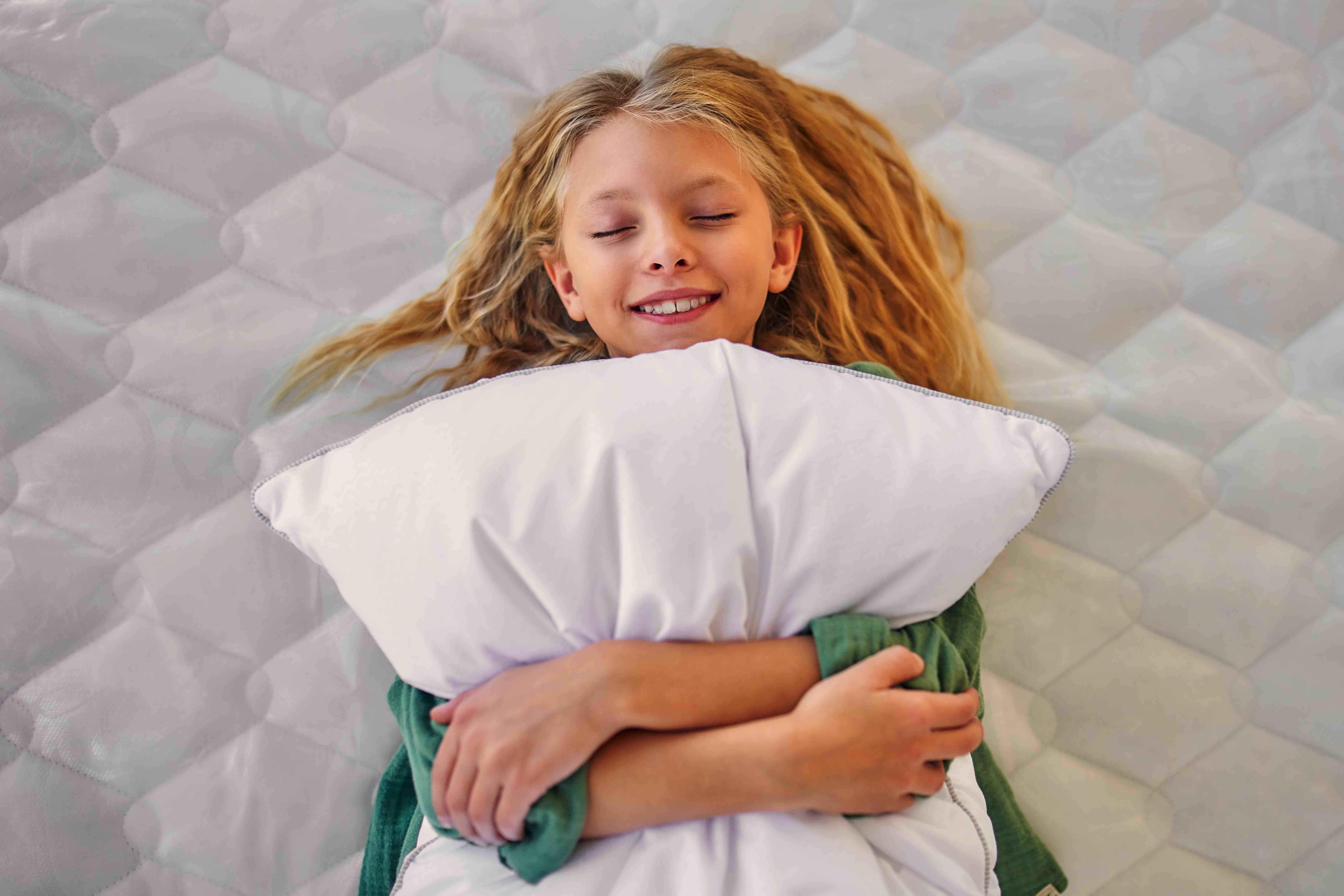 girl lying on mattress clutching a pillow